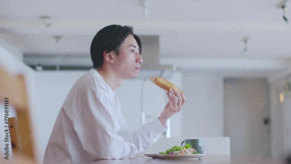 リビングにて朝食を食べる若い日本人の男性