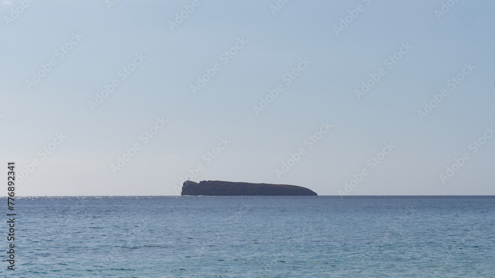 Minimalistic photo of a Molokini Crater with a clear blue sky in the background near the island of Maui, Hawaii USA