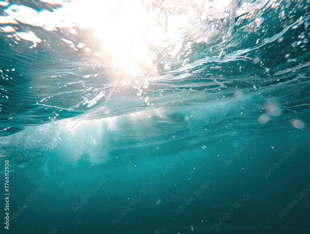 Close up underwater photo of giant waves in the middle of the ocean with bright sunlight breaking through them, turquoise color of water