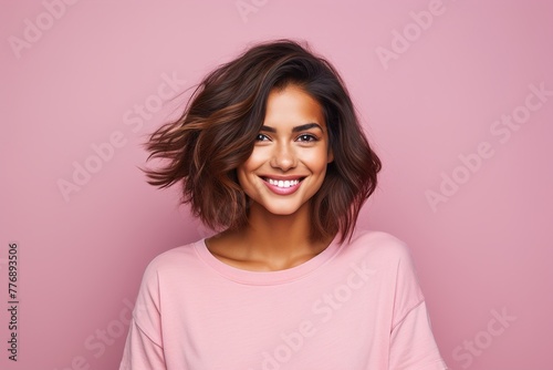 A woman with short brown hair and a pink shirt is smiling