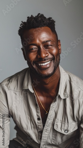 Joyful man with a contagious smile. Close-up portrait of a happy man with a bright smile and stylish hair, wearing a casual shirt and necklace