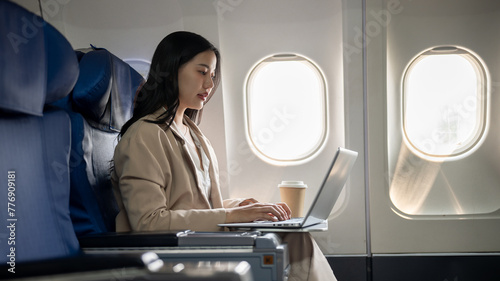 Fotografie A hard-working Asian businesswoman is focusing on working on her laptop computer during the flight