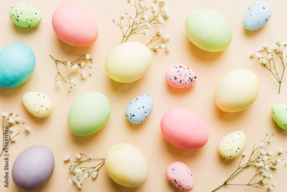 Happy Easter composition. Easter eggs on colored table with gypsophila. Natural dyed colorful eggs background top view with copy space