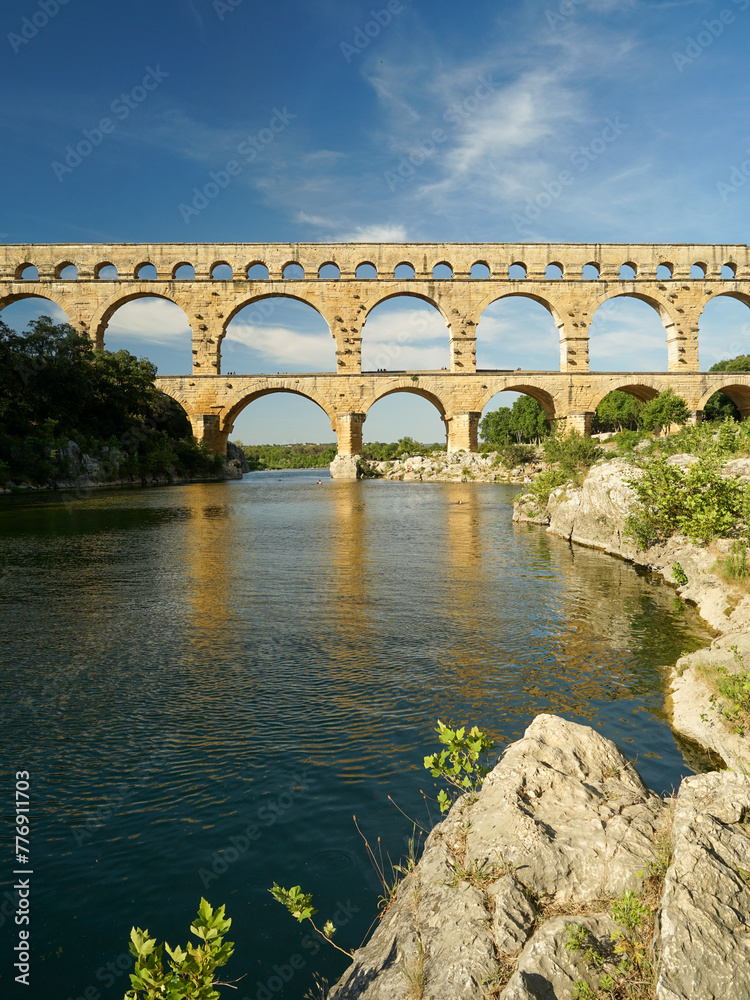 Pont du Gard famous aqueduct arched bridge mirroring in Gardon river, popular tourist landmark in France