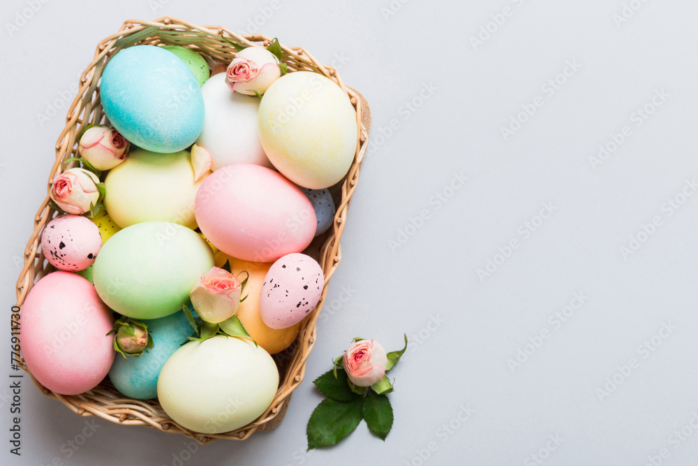 Happy Easter. Easter eggs in basket on colored table with yellow roses. Natural dyed colorful eggs background top view with copy space Happy Easter. Easter eggs in basket on colored table with yellow roses. Natural dyed colorful eggs background top view with copy space