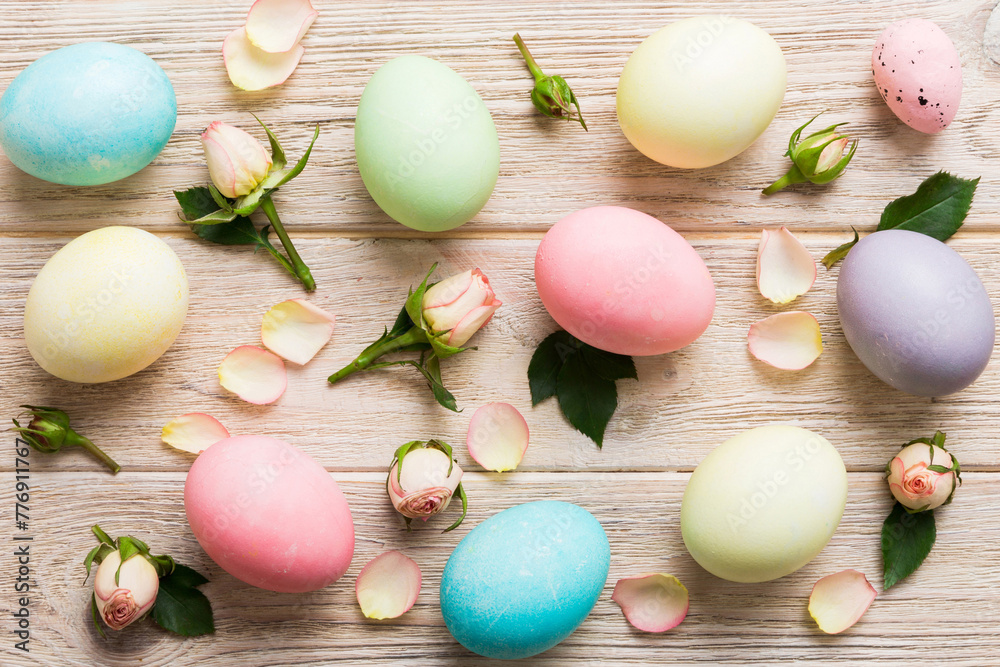Happy Easter. Easter eggs on colored table with yellow roses. Natural dyed colorful eggs background top view with copy space Happy Easter. Easter eggs on colored table with yellow roses. Natural dyed colorful eggs background top view with copy space