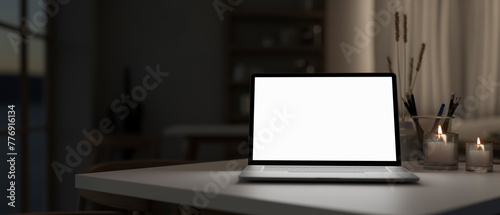 A white-screen laptop computer mockup on a table in a modern dark room.