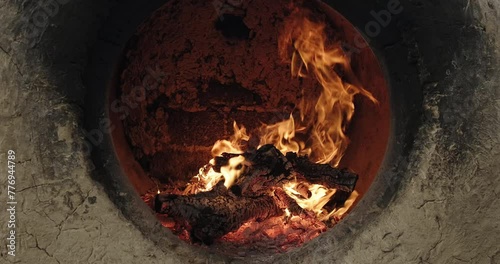 Firewood burns brightly in a clay Uzbek oven tandoor to bake samsa or bread. Burning fire in stone oven. Uzbek bakery photo