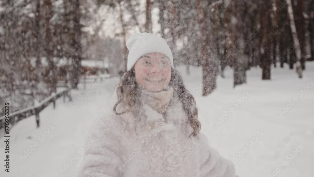 Portrait of a smiling happy woman throwing snow up. Beautiful playful girl enjoying a walk outdoors, having fun during winter holidays. Happy pleasure concept Portrait of a smiling happy woman throwing snow up. Beautiful playful girl enjoying a walk outdoors, having fun during winter holidays. Happy pleasure concept