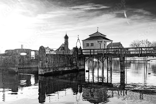 alte Badehäuser und verfallener Hafen am Bodensee vor der Halbinsel Wasserburg mit der Kirche St. Georg