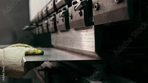 Plate steel worker hands put of industrial bending machine metal press industry equipment factory. Worker holds steel sheet on bending machine forms steel products. Bending metal machine. Metalworking