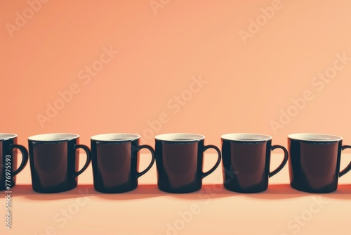 Mugs of black coffee in rows against peach background