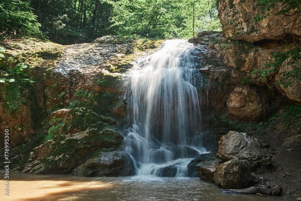 Fototapeta premium A beautiful natural waterfall in a mountain landscape. Clean mountain river
