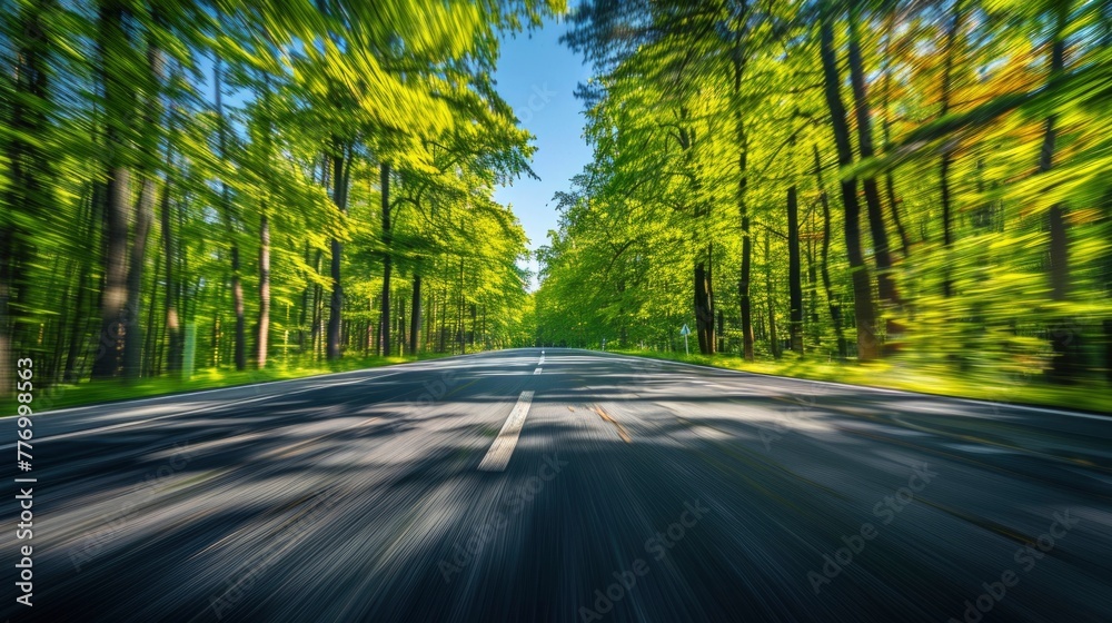 Obraz premium Motion blur of a straight asphalt road in the middle of the forest during the day