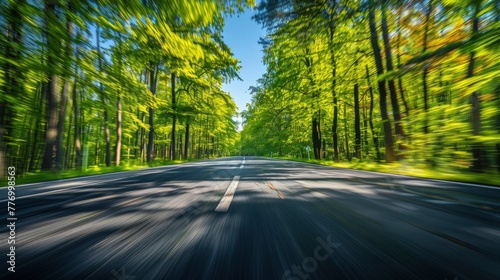 Motion blur of a straight asphalt road in the middle of the forest during the day