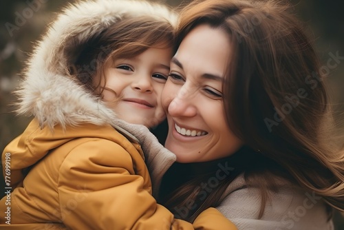 Cheerful mother and daughter sharing a hug in winter coats, smiles lighting up their faces.