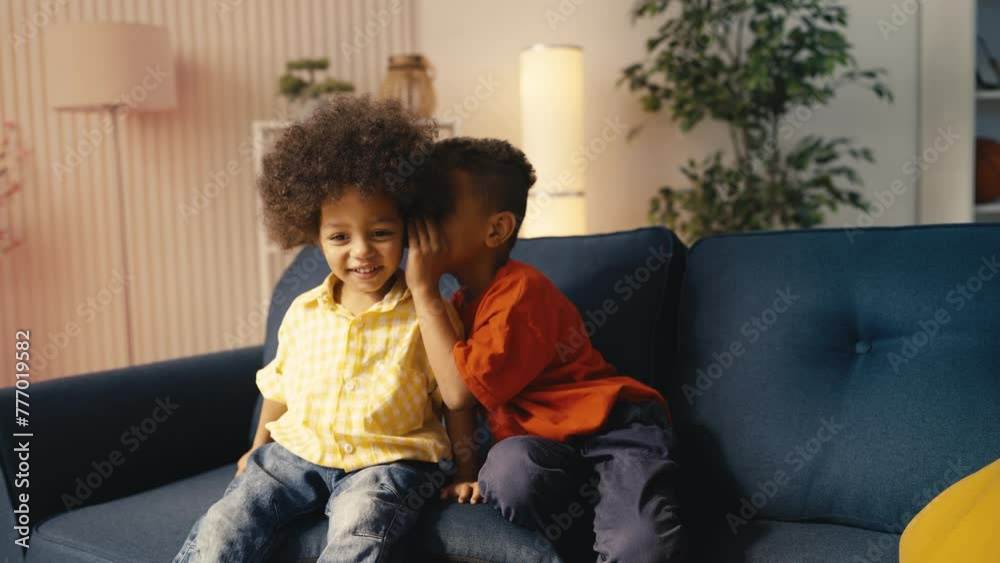 African American boy whispers a secret in little brother's ear and they laugh African American boy whispers a secret in little brother's ear and they laugh