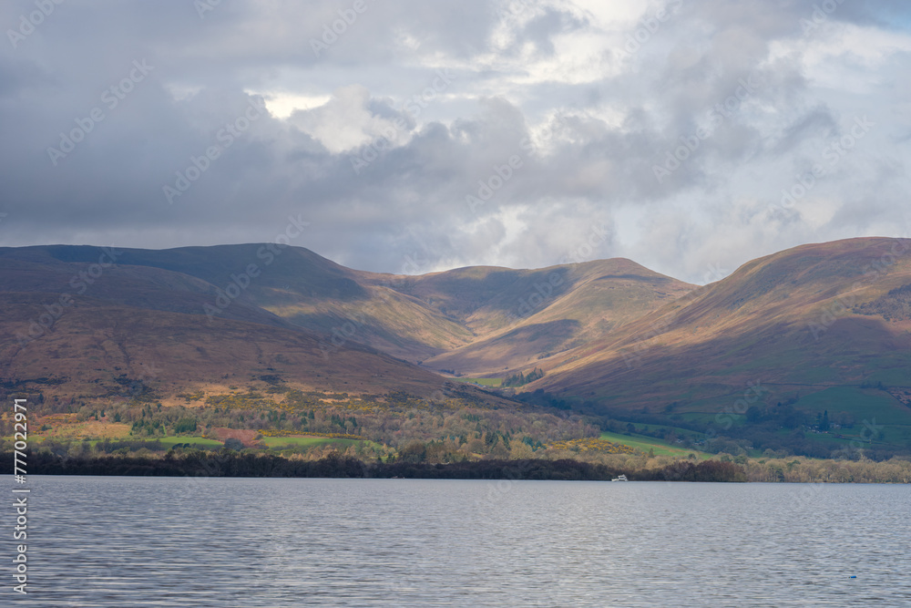 Cloudy sunny sky over Scottish hills by a lake (loch)