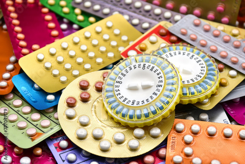 Oral contraceptive pill on pharmacy counter with colorful pills strips background.