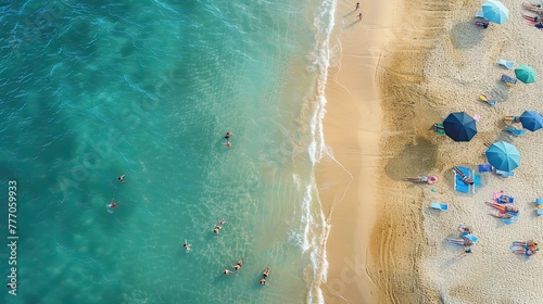 This bird's-eye view captures the lively scene of a sunny beach, where people are swimming and lounging under colorful umbrellas on the golden sands beside the sparkling sea.. photo