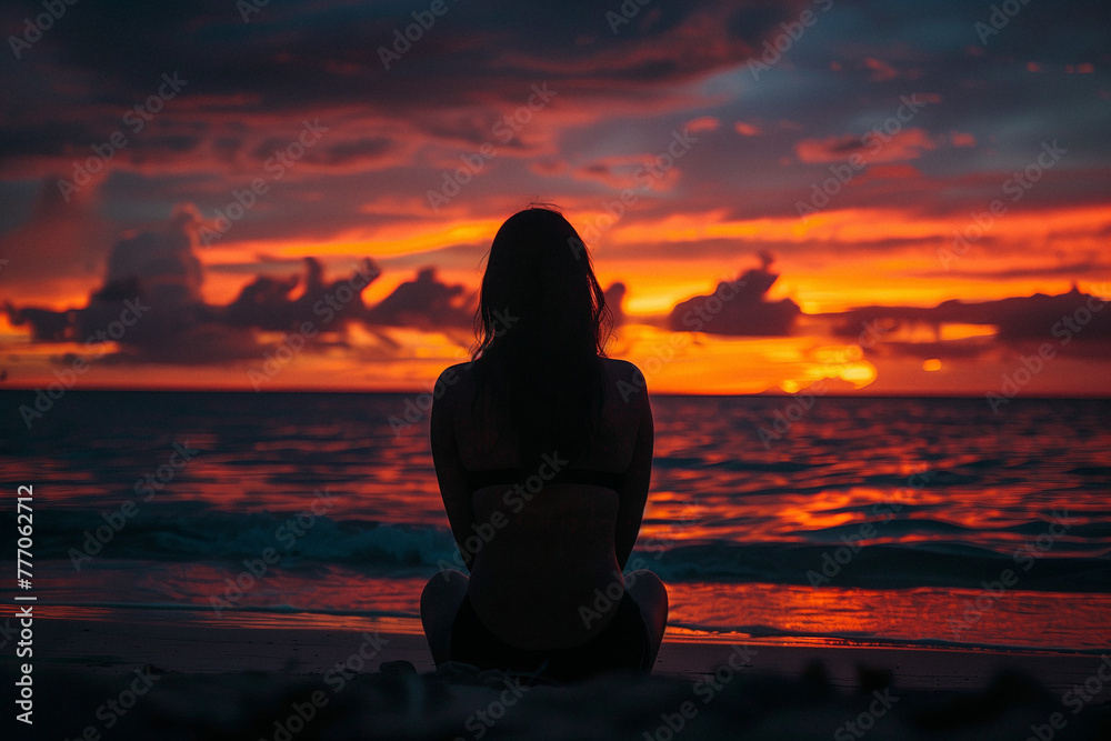 Silhouette of a person sitting peacefully on the beach at sunset.