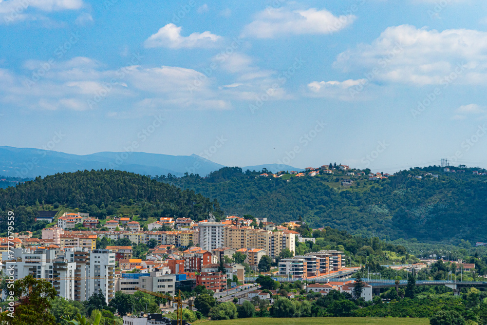 A view of Coimbra City under a beautiful clear sky, with trees and buildings. Landscape background and wallpaper.