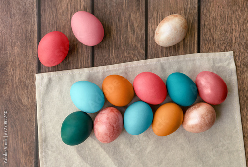 A variety of colorful Easter eggs rest on a white cloth atop a wooden table, creating a sweet and festive confectionery display of food ingredients © Маргарита Трушина