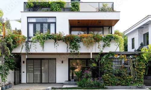 A white minimalist house with an exterior wall decorated with green plants and flowers photo