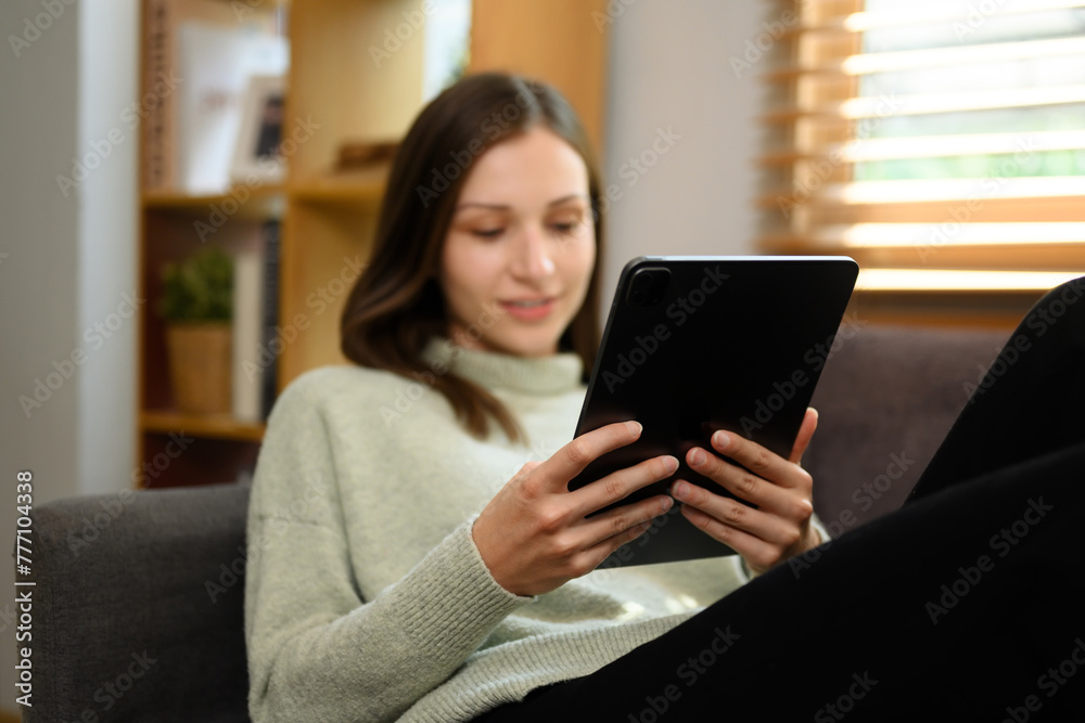 Carefree caucasian woman relaxing on couch and using digital tablet Carefree caucasian woman relaxing on couch and using digital tablet