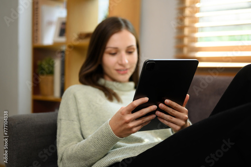 Carefree caucasian woman relaxing on couch and using digital tablet