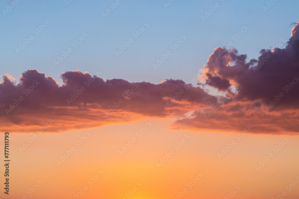 Serene sunset sky with vibrant orange glow and scattered clouds. Atmosphere background or wallpaper with copy space