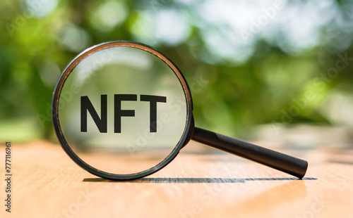 NFT acronym through magnifier on nature background. photo