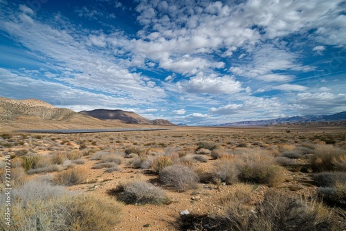 A wide open field with mountains in the background, under a clear sky