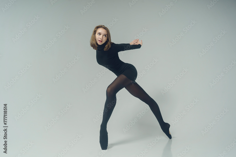 a young ballerina in a black dress and sunglasses total black demonstrates choreography on pointe shoes