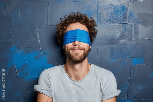 Blindfolded man against blue textured wall smiling. Generative AI image photo