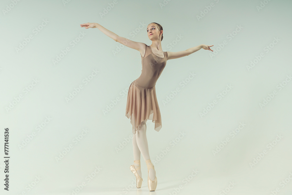 young teenage ballerina poses in a photo studio shows ballet and dance steps