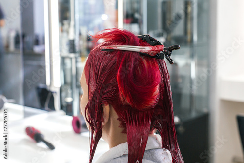 hairdresser colorist client sits in a chair with his back turned, hairdresser dyes hair red, bleaches hair roots in beauty salon, concept of beauty and hairdressing training. hair clips.