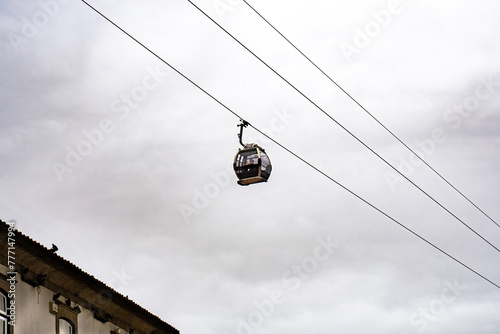 Gondola or cabin of the cable car from the Vila Nova de Gaia neighborhood suspended on the hanging cables transporting tourists from the Don Luis I bridge to the Porto promenade under a cloudy sky. photo