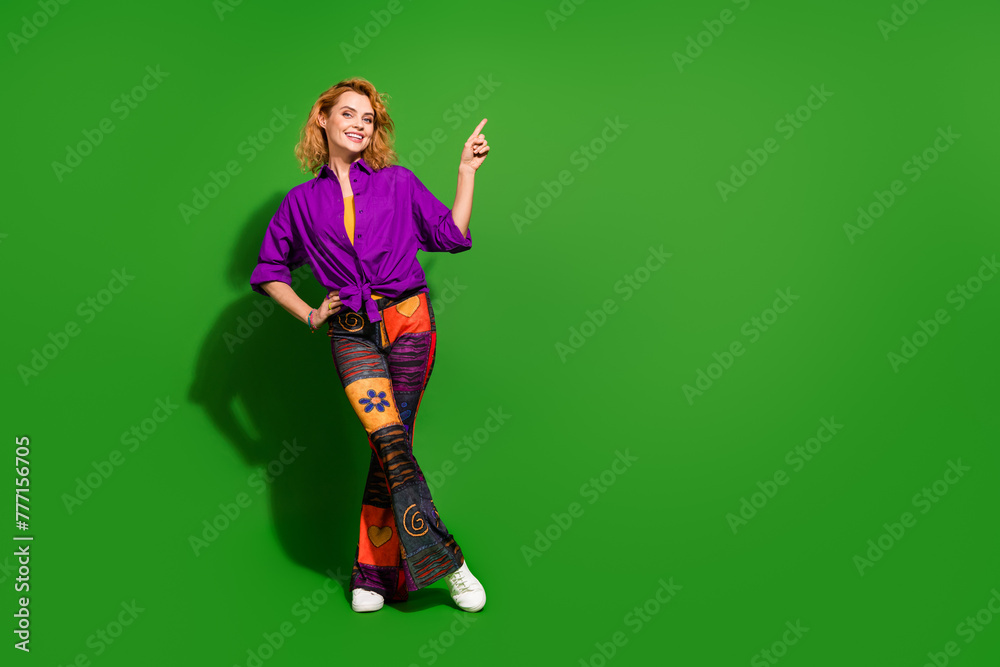 Photo portrait of lovely young lady point empty space poster dressed stylish violet clothes isolated on green color background Photo portrait of lovely young lady point empty space poster dressed stylish violet clothes isolated on green color background