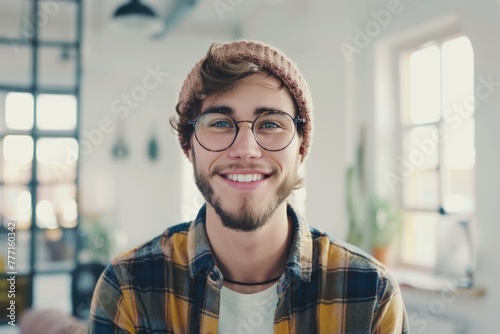 Geeky hipster in white room with windows smiling at camera. photo