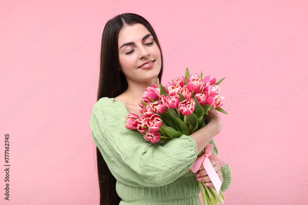 Happy young woman with beautiful bouquet on dusty pink background