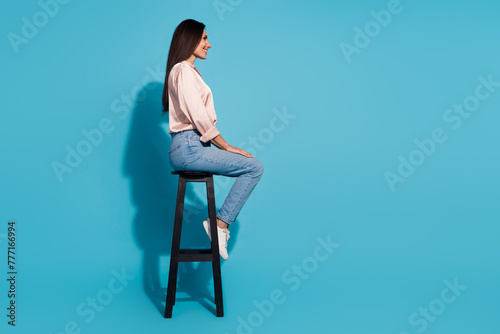 Wallpaper Mural Full length photo of cute positive woman wear silky blouse sitting chair looking empty space isolated blue color background Torontodigital.ca