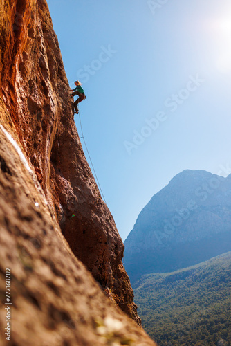 A girl climbs rocks, a rock climber against the backdrop of a mountain, a sporty girl is engaged in rock climbing. Turkey.