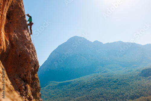 A girl climbs rocks, a rock climber against the backdrop of a mountain, a sporty girl is engaged in rock climbing. Turkey.