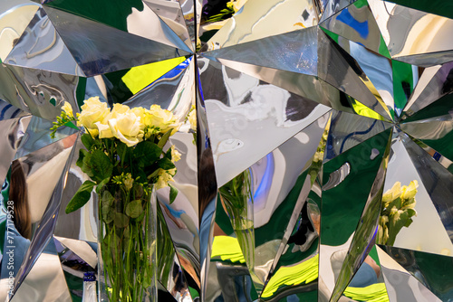 Table with a vase of flowers and a bottle of champagne against a bright mirror tringular background photo