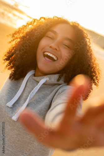African American Biracial Female Woman Teenage Girl Smiling and Reaching to Camera on a Beach at Sunset