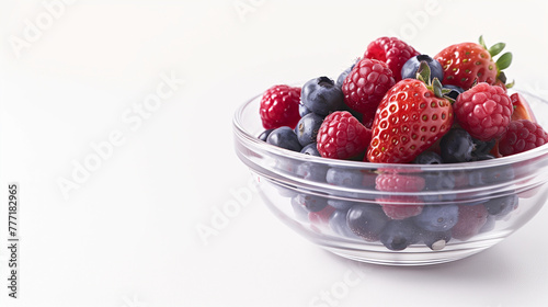 Assorted fresh berries in a glass bowl on white background. Studio shot with copy space. Healthy eating and organic food concept for design and print.