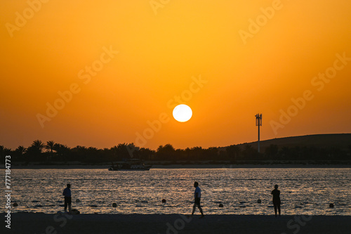 People walking along Corniche Beach in Abu Dhabi during warm evening with sunset in  United Arab Emirates © Savvapanf Photo ©