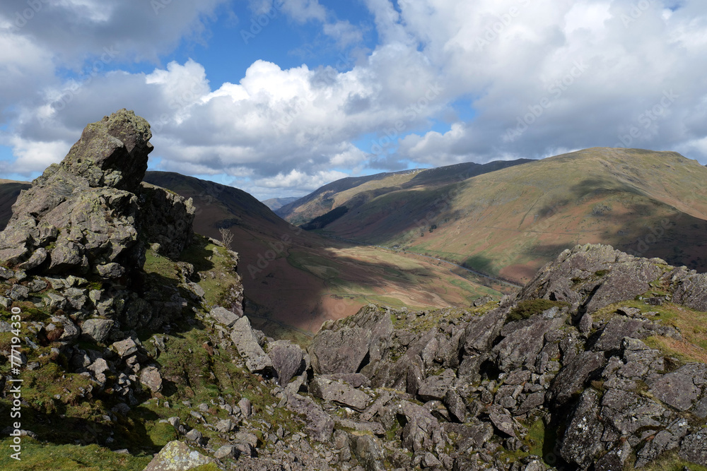 Rocky outcrop of the Lion and Lamb at the top of Helm Crag in the Lake District National Park. Cumbrian fells can be seen in the backdrop.