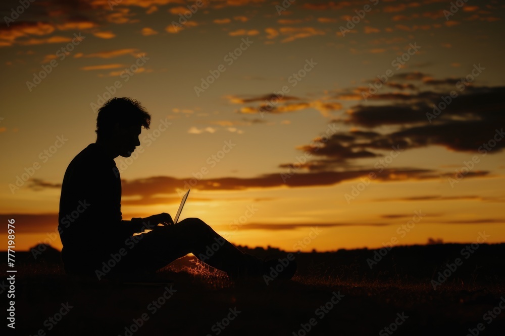 Silhouette of young man with laptop